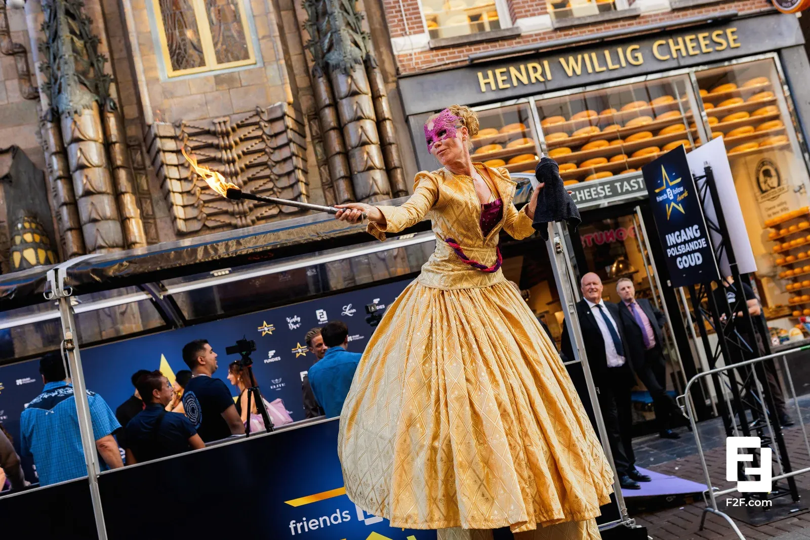 A fire performer in a golden gown welcomes guests at the entrance of a business event